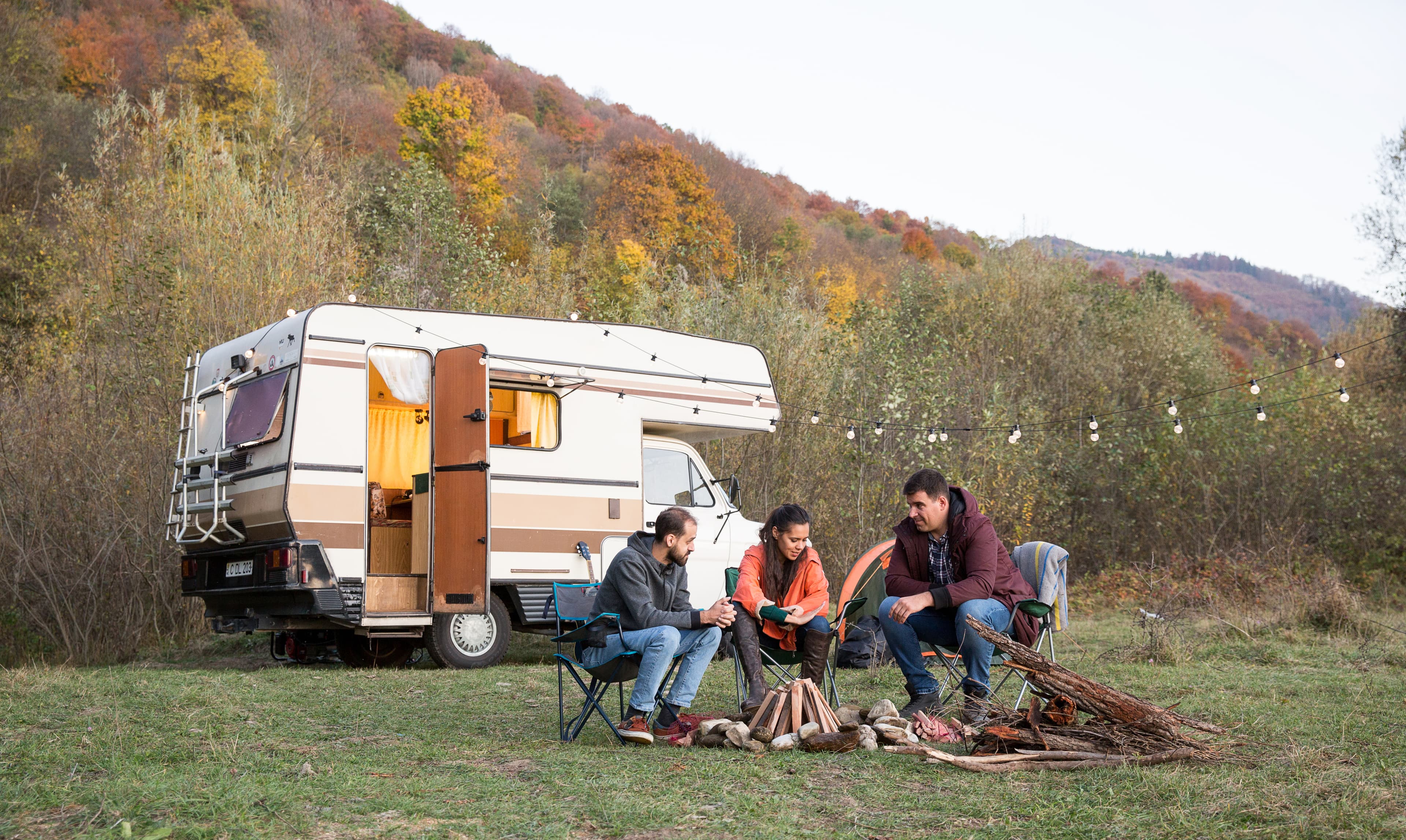 Caravan staat op een camping aan een meer met bergen op de achtergrond